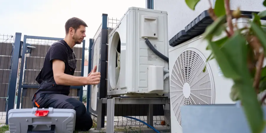 Luft-Wasser-Wärmepumpe für das Fertighaus installieren Techniker installiert eine Luft-Wasser-Wärmepumpe an einem modernen Fertighaus in Österreich